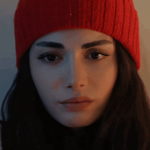 a woman wearing a red beanie looks at the camera
