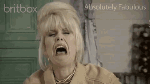 a woman is making a funny face with her mouth open and a christmas tree in the background .