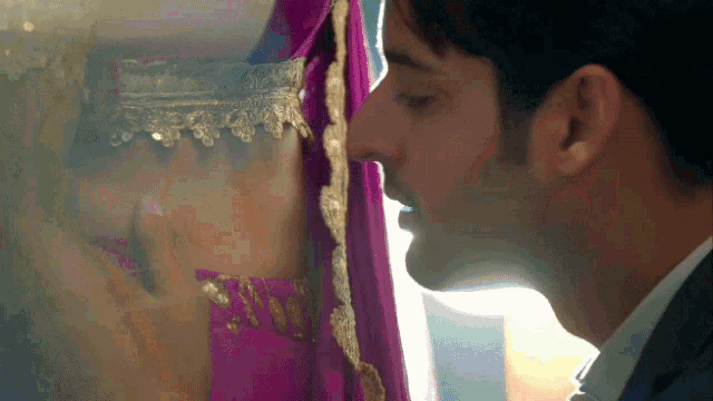 a man in a suit kisses a woman in a pink sari