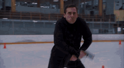 a man in a black jacket is holding a hockey stick on a rink