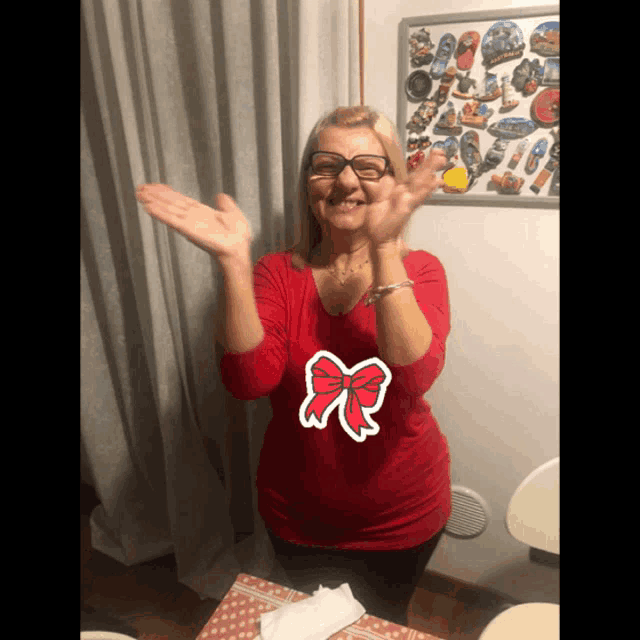 a woman wearing glasses and a red shirt with a bow on it