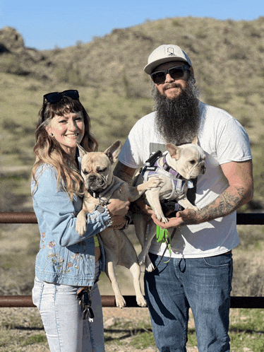 a man with a beard holds two dogs in his hands