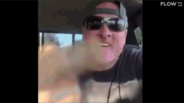a man wearing sunglasses and a hat is in a car