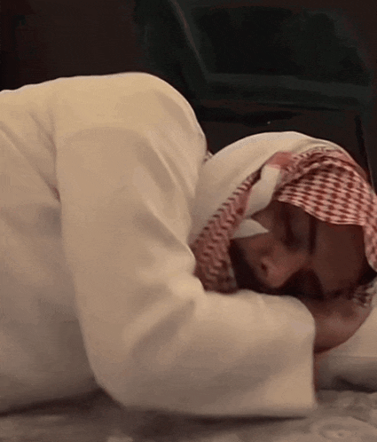 a man wearing a head scarf is laying on the floor with his head on a pillow