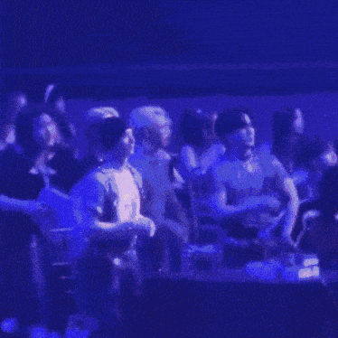 a group of people are sitting in a dark room with blue lights