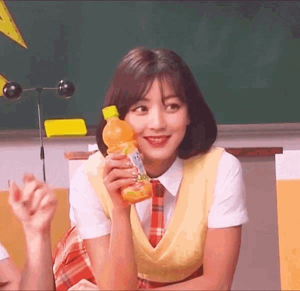 a girl is holding a bottle of orange juice and smiling
