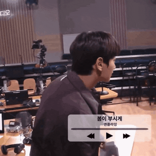 a man stands in front of a microphone in a room with korean writing on the screen