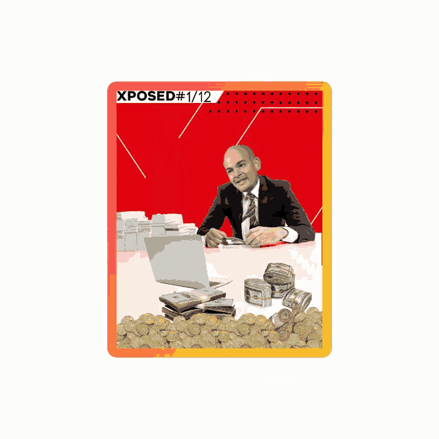 a man in a suit sits at a desk with a laptop and stacks of money behind him