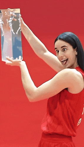 a woman in a red tank top holds a trophy in her hands