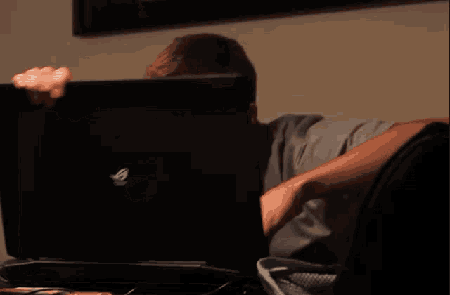 a man sitting in front of a laptop with a sticker on the back that says ' monkey '