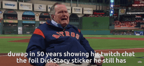 a man wearing an astros sweatshirt sits on the baseball field