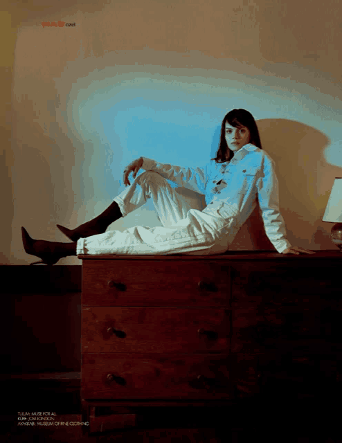a woman sits on a wooden dresser with the word mag on the top
