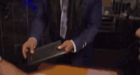 a man in a suit and tie with long hair is holding a wallet .