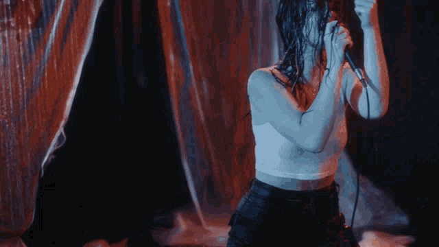 a woman singing into a microphone with her hair wet