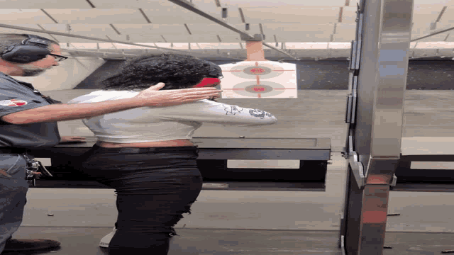 a man and a woman are aiming a gun at a target with a red center