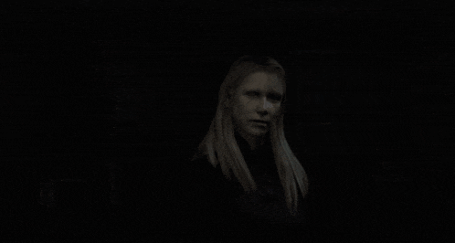 a woman with long blonde hair is standing in the dark