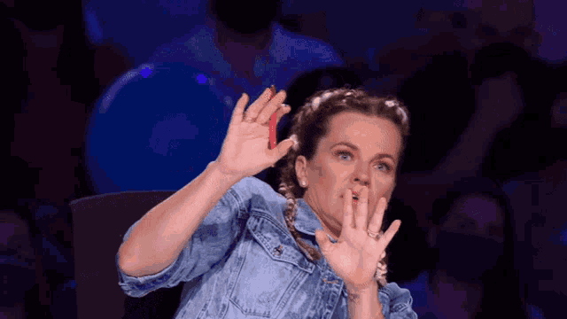 a woman in a denim jacket is making a funny face