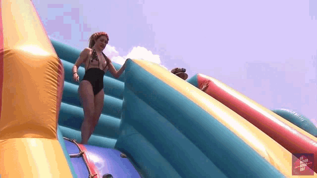 a woman in a black swimsuit is standing on a bouncy house