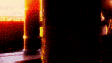 a dark room with a pillar in the foreground and a window in the background