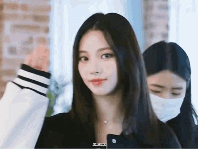 a girl wearing a face mask is standing next to another girl .