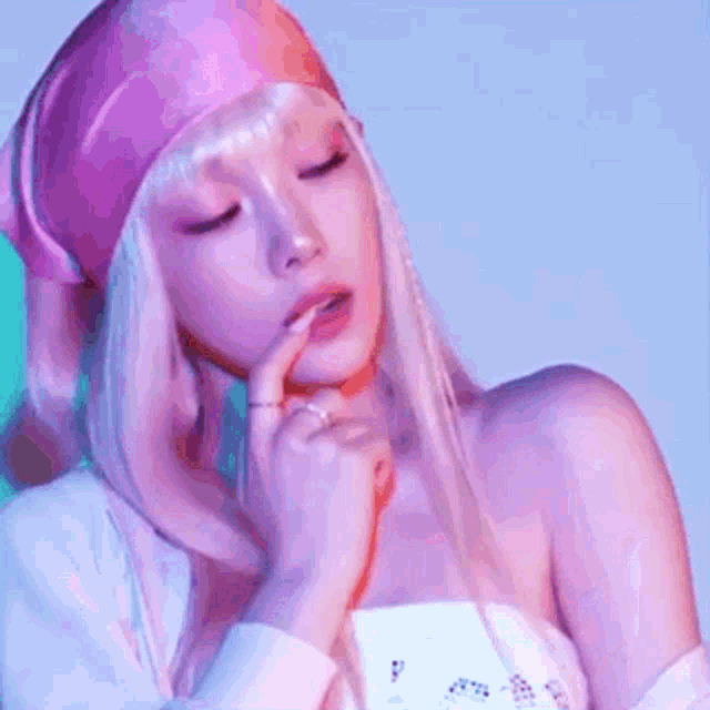 a woman with blonde hair is wearing a pink headband and holding her finger to her mouth .