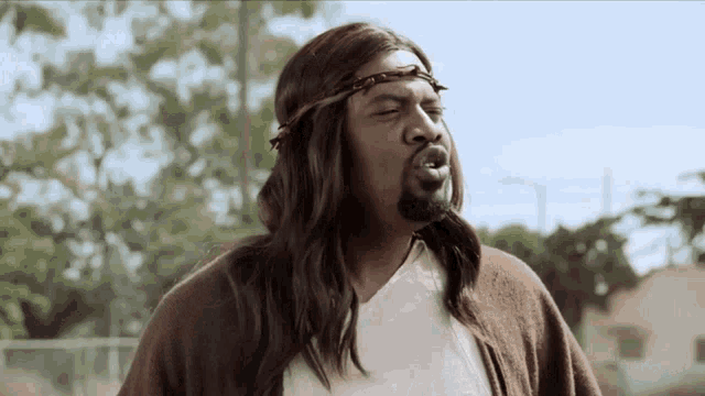 a man dressed as jesus with long hair and a crown of thorns on his head