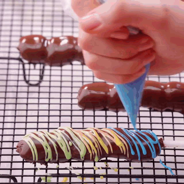 a person is decorating a chocolate bar with rainbow colored frosting