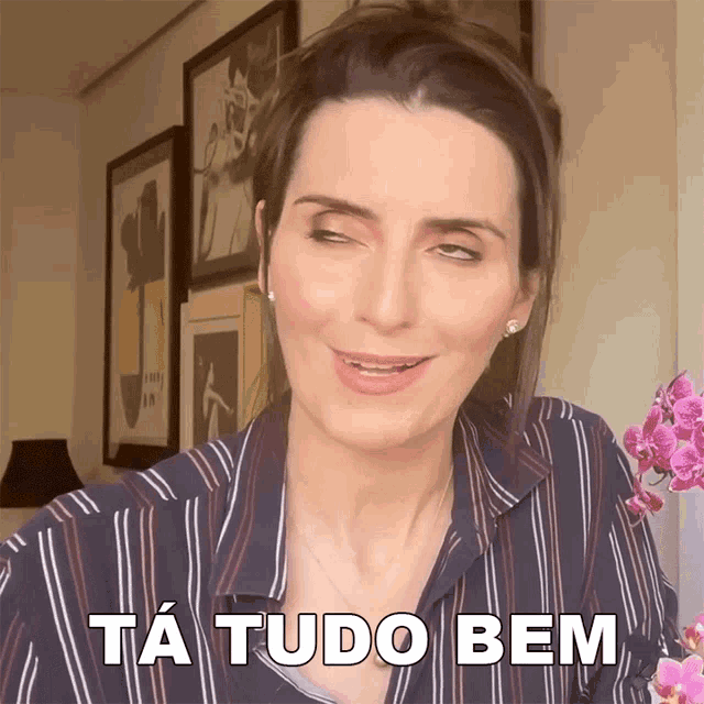 a woman in a striped shirt is making a funny face and says ta tudo bem