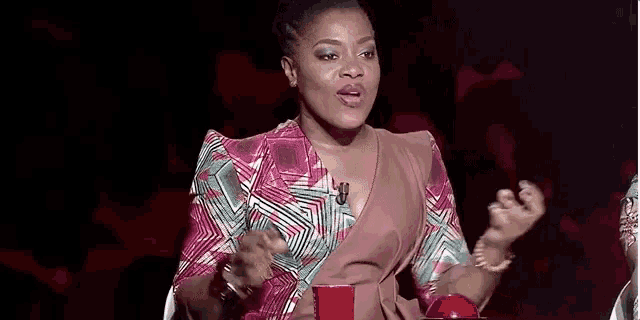 a woman in a colorful dress is sitting at a table in front of a microphone and a red cup .