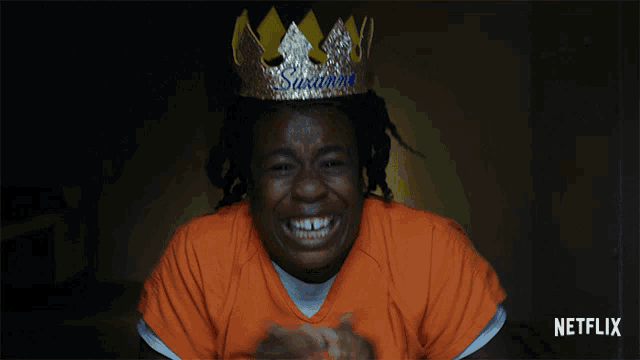 a woman wearing an orange shirt and a crown with the name suzanne on it