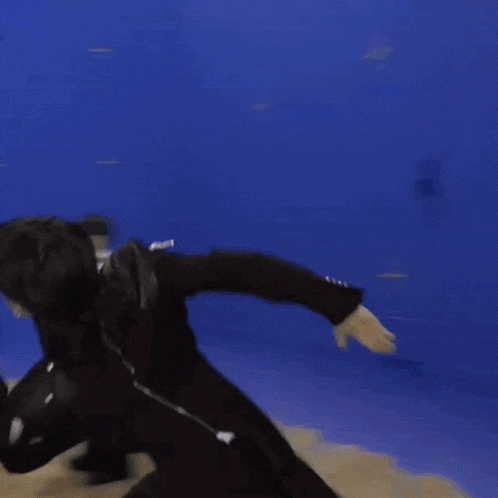 a person in a black suit is running in front of a blue background