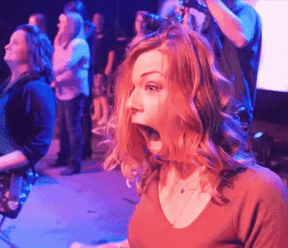 a woman with a surprised look on her face is standing in front of a crowd