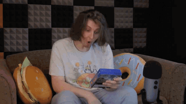 a man sitting on a couch with a surprised look on his face holding a box