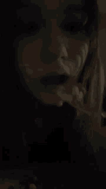 a close up of a woman 's face with red lips in the dark