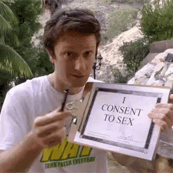 a man in a white shirt holds up a sign that says i consent to sex