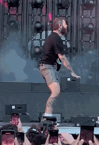 a man with a beard is dancing on a stage while a crowd watches