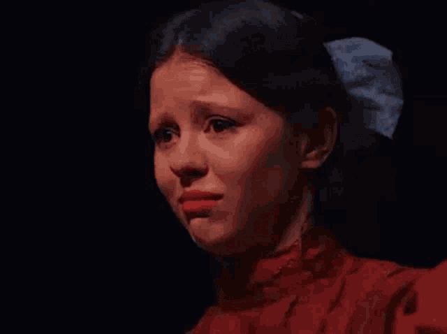 a young woman in a red dress is crying in the dark .