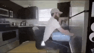 a man with a beard is sitting in a chair in a kitchen .