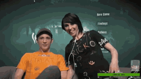a man wearing an orange treat shirt sits next to a woman wearing a black shirt that says ricko on it