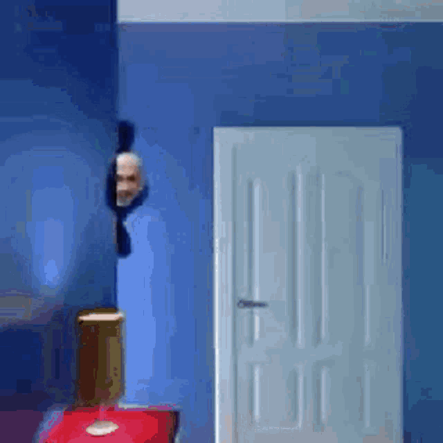 a blue wall with a white door and a lamp on a table