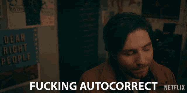 a man is smiling in front of a sign that says fucking autocorrect netflix