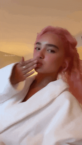 a woman with pink hair blowing a kiss with the words i love it here behind her