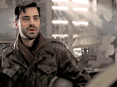 a man with a beard is wearing a jacket and scarf and holding a helmet