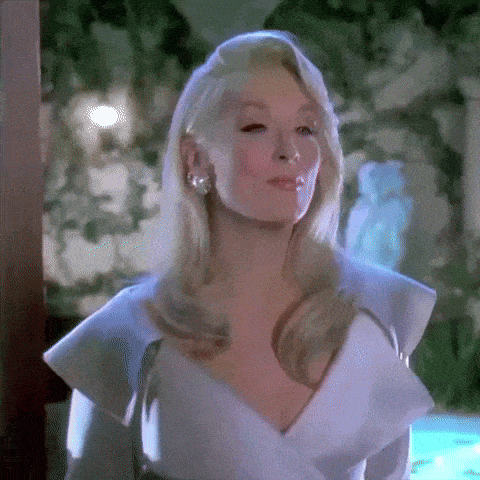 a woman in a white dress and earrings is standing next to a pool .