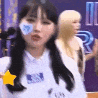 a woman with a star on her shirt is dancing in front of a purple wall .
