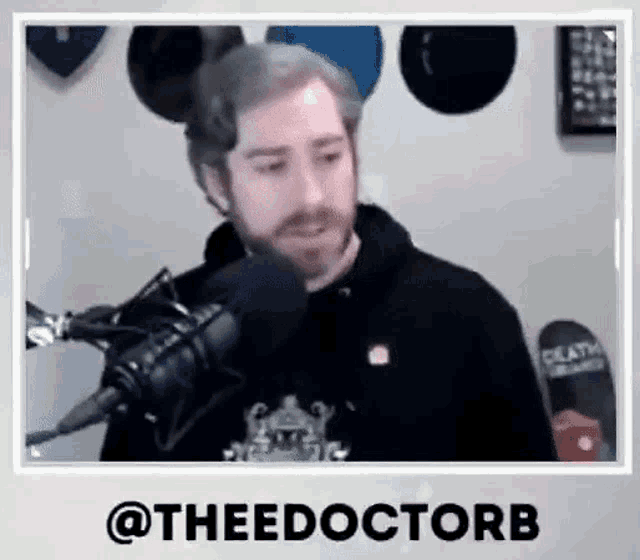 a man with a beard is talking into a microphone in a room .