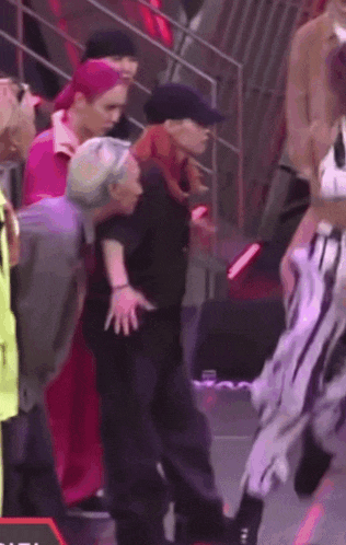a group of people are standing on a stage and one of them is dancing .