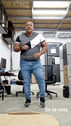 a man in a gray shirt and blue jeans is dancing in a room with the words se te nota below him