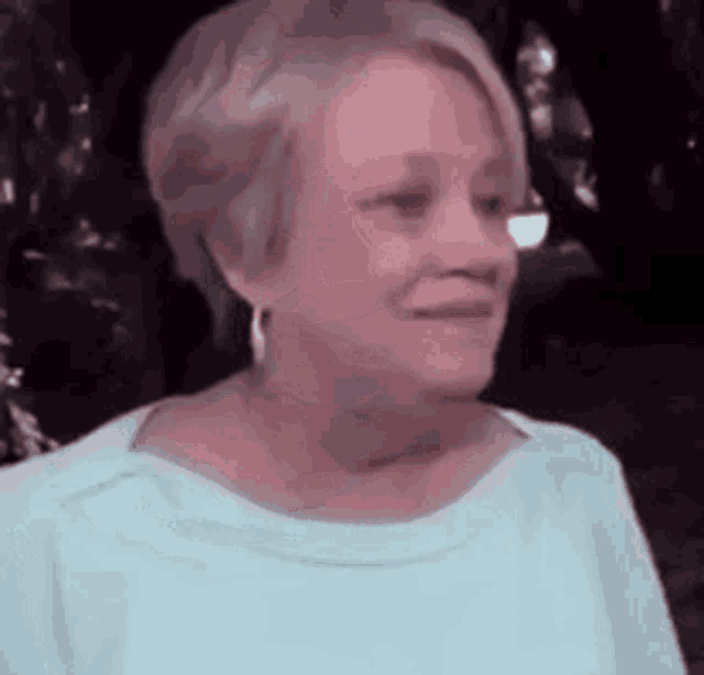 a woman wearing a blue shirt and earrings is smiling and looking at the camera .