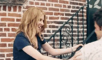 a woman is putting her hand on a man 's back in front of a brick building .